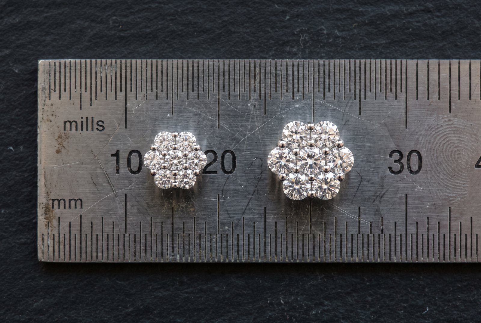 9mm and 12mm moissanite cluster stud earrings placed on a steel millimeter ruler, showing their true face size side by side