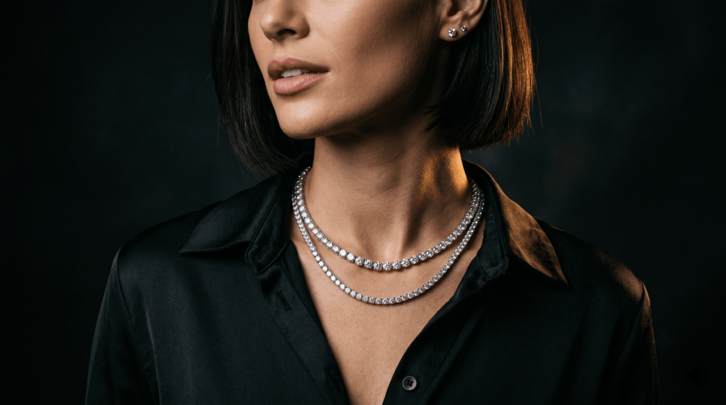 Woman in a black satin shirt wearing two layered moissanite tennis chains at different lengths with stud earrings