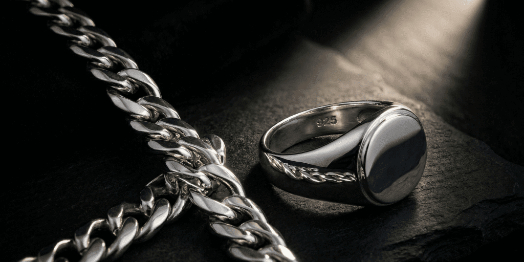 Polished .925 sterling silver signet ring stamped 925 next to a heavy curb chain on dark stone