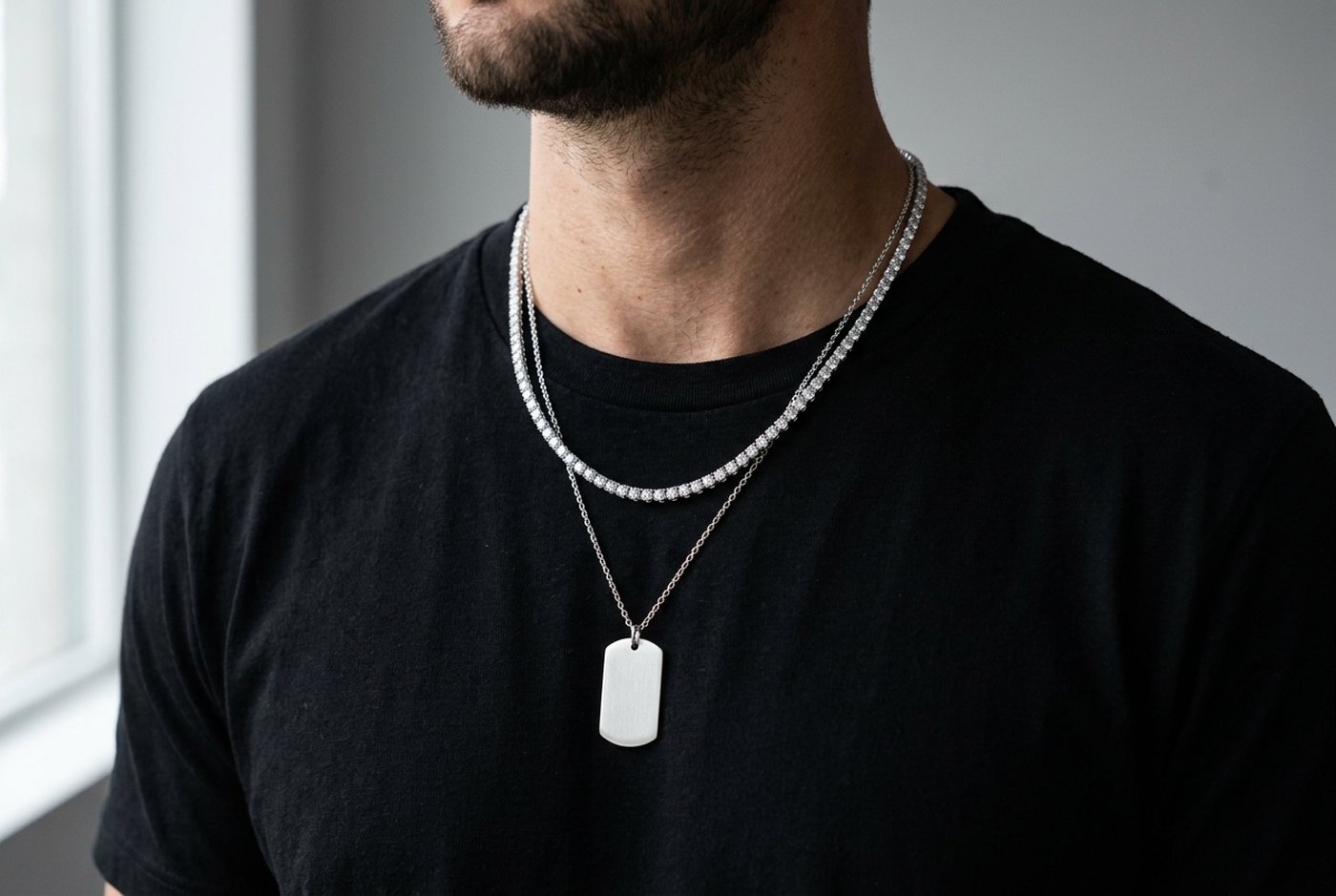 Man in a black t-shirt wearing a sterling silver moissanite tennis chain layered with a plain silver dog tag pendant