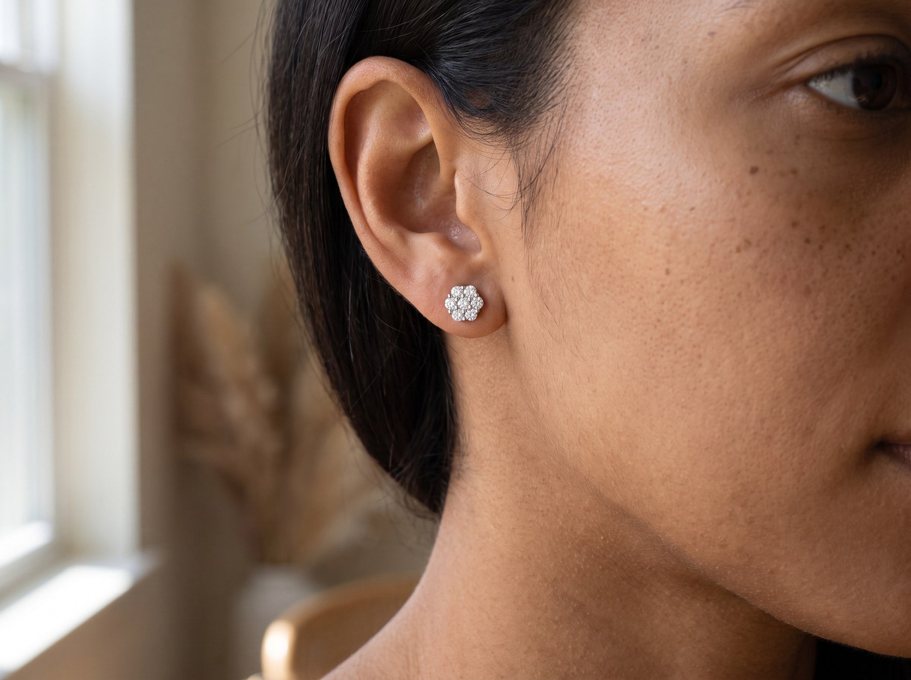 A moissanite stud worn at actual size, cropped close on the ear