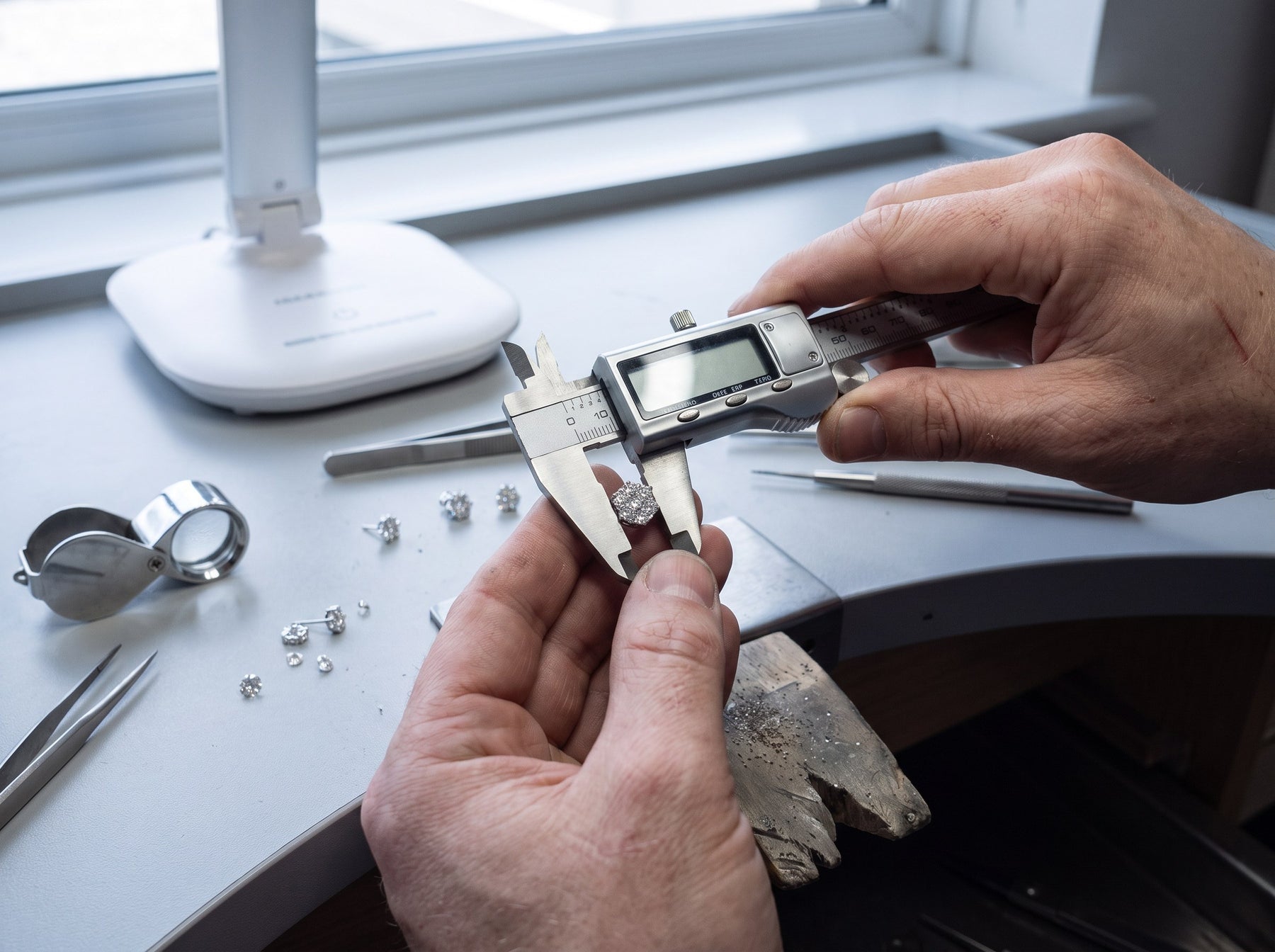 Calipers measuring a moissanite stone at the workbench
