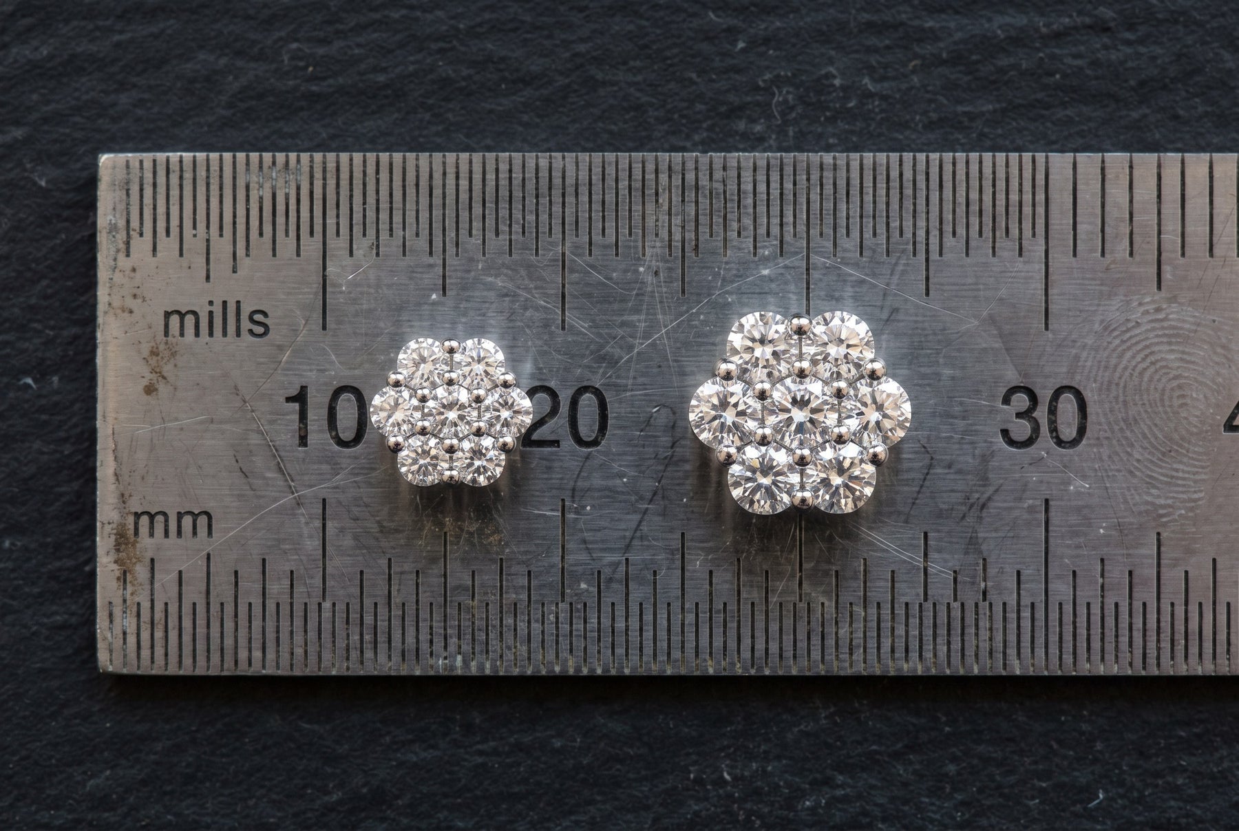 Moissanite studs laid on a ruler for size comparison