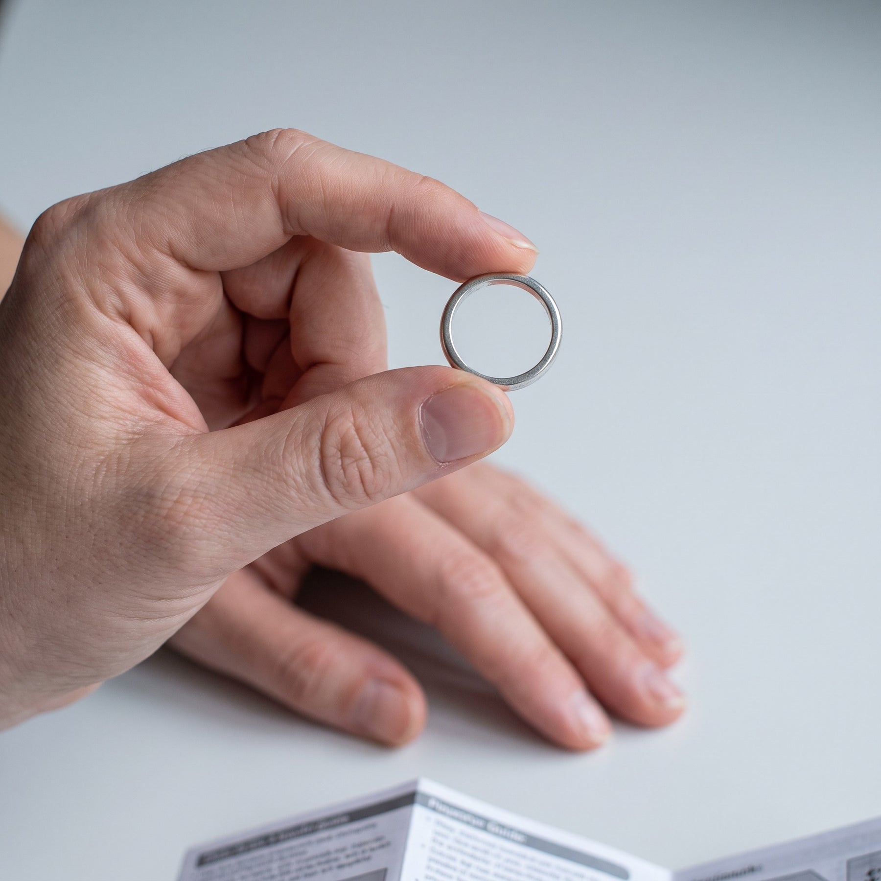 Step one of finding your ring size: a ring that already fits the same finger, held in the hand