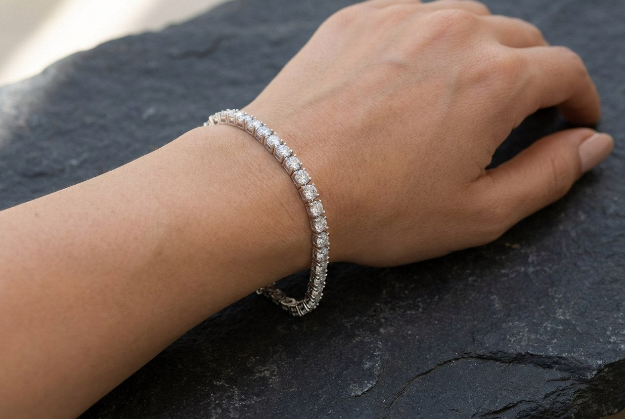 A round-cut moissanite tennis bracelet fastened on a wrist, sitting in a relaxed fit toward the hand