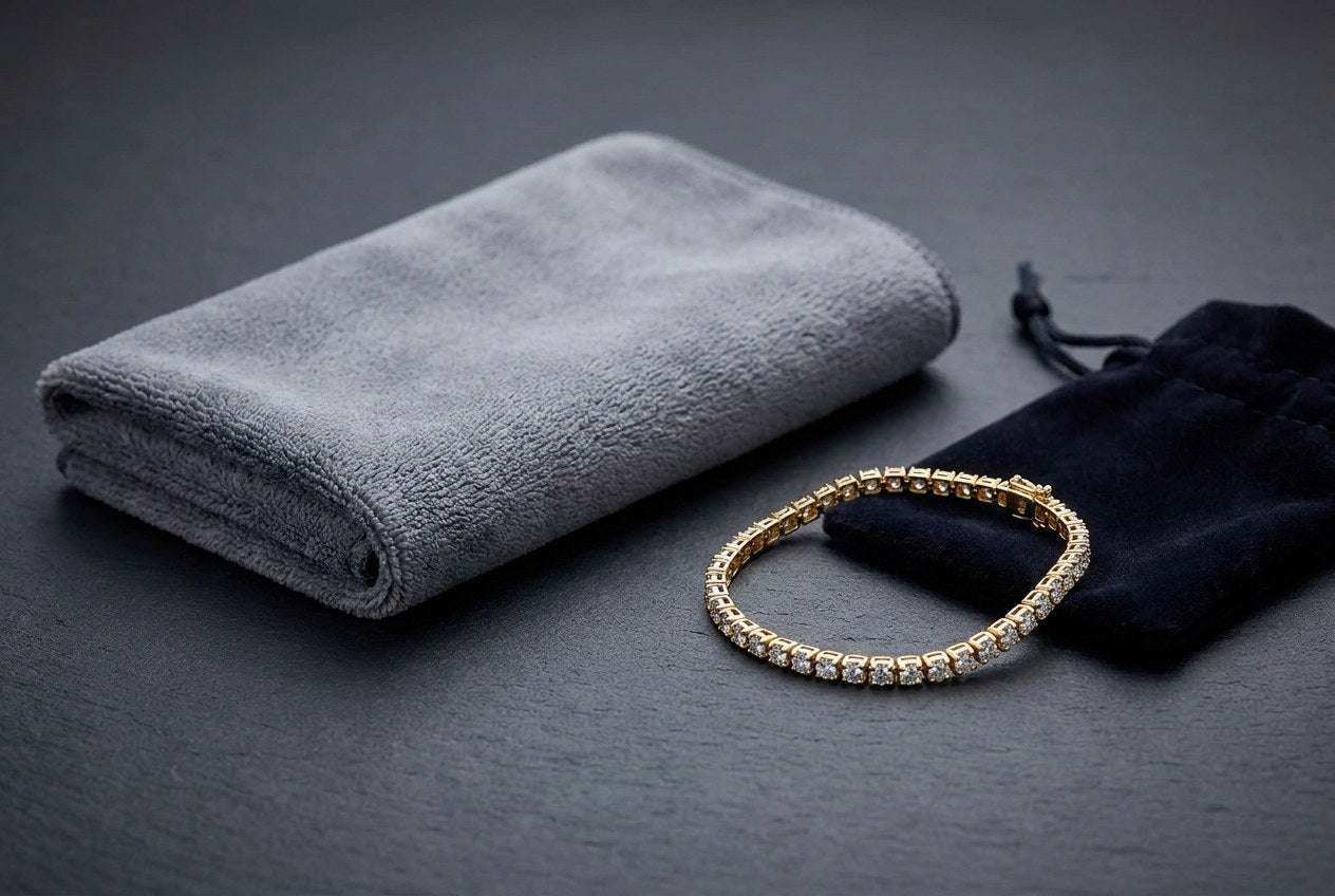 A soft grey cloth, a gold finish moissanite tennis bracelet and a dark storage pouch arranged on a slate surface