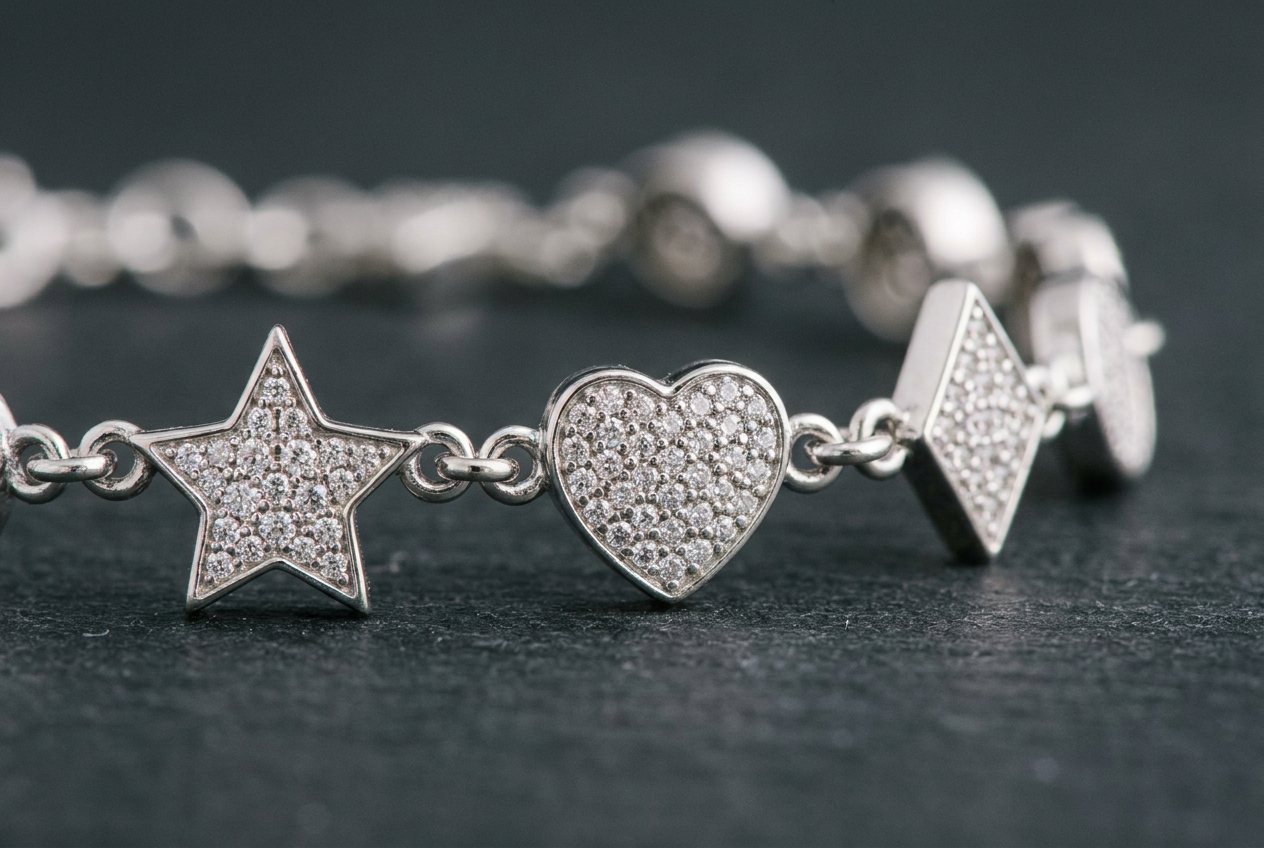 Close detail of a sterling silver charm station bracelet with paved star, heart and kite shapes joined by fine links