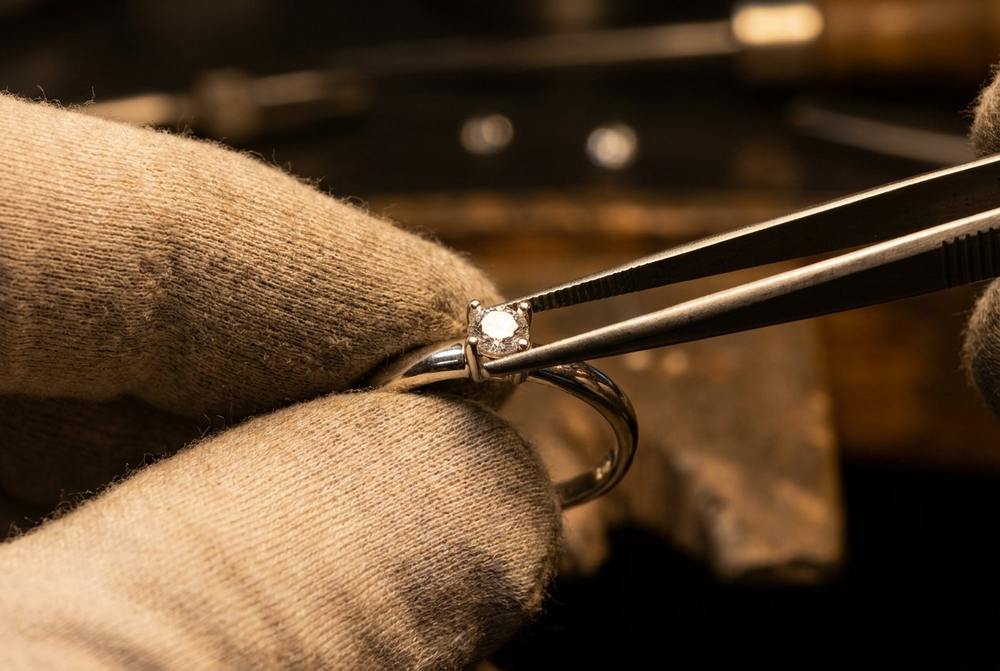 A jeweler using tweezers to place a small moissanite stone into a sterling silver setting