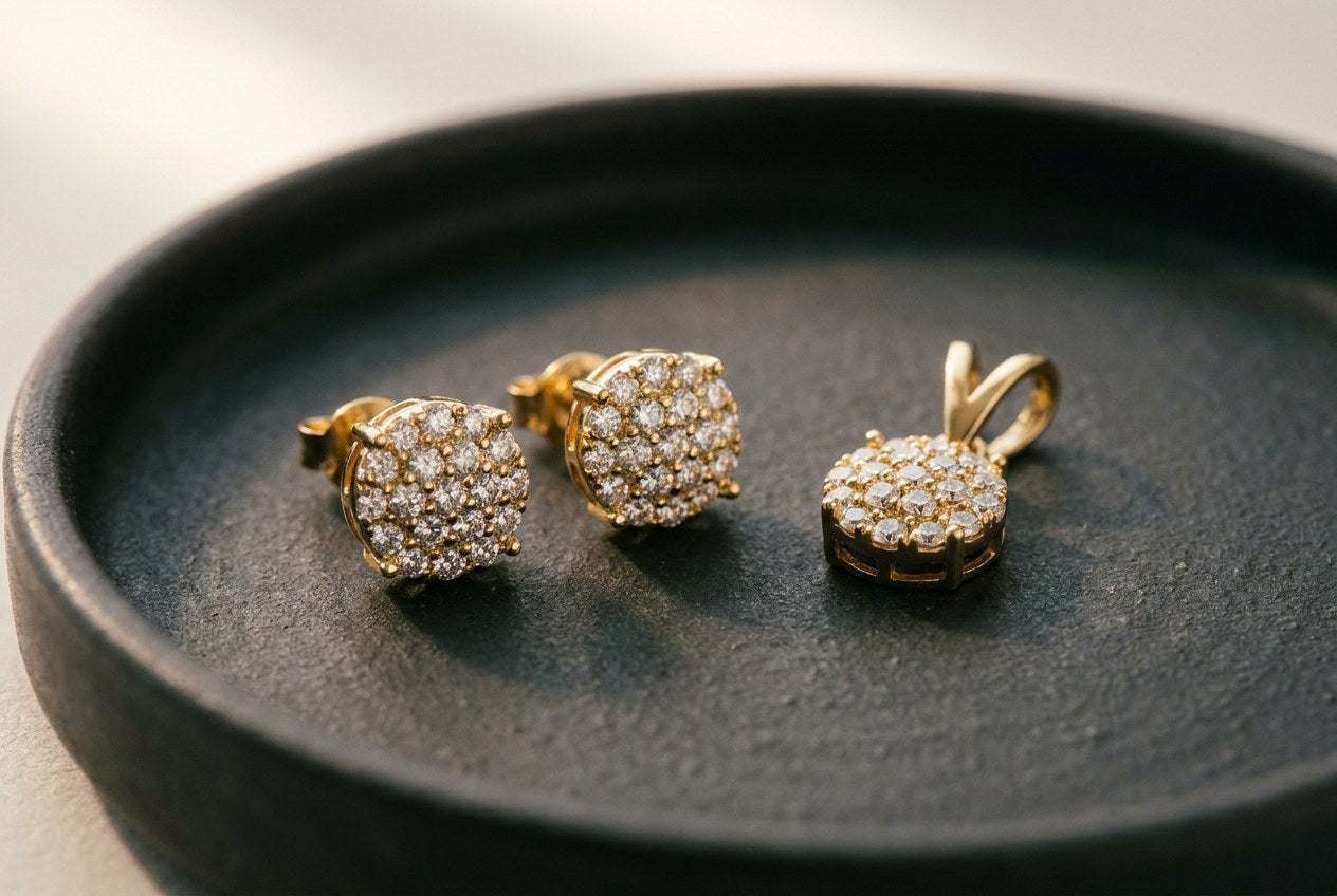 Gold finish moissanite cluster stud earrings and a matching pendant resting on a dark ceramic tray