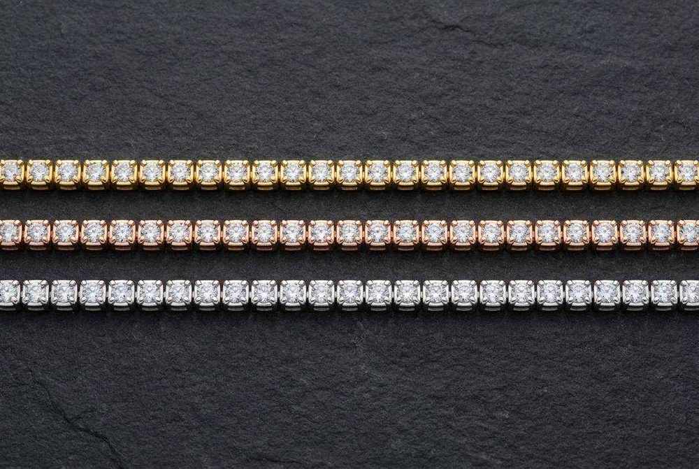Three moissanite tennis bracelets in gold, rose gold and silver finishes photographed from above in a row
