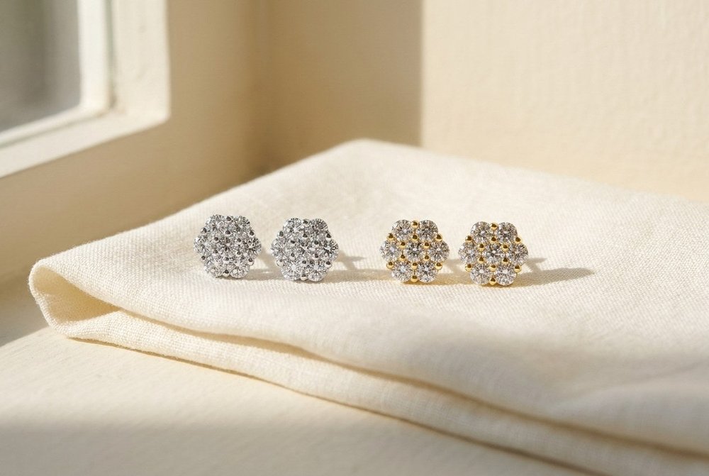 Silver and gold moissanite cluster stud earrings resting side by side on ivory linen