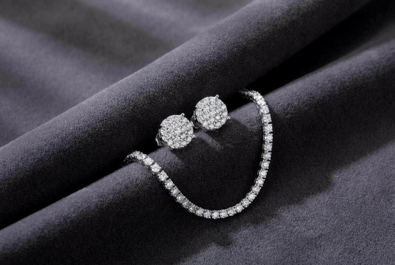Sterling silver moissanite cluster stud earrings and a tennis chain arranged on dark charcoal velvet