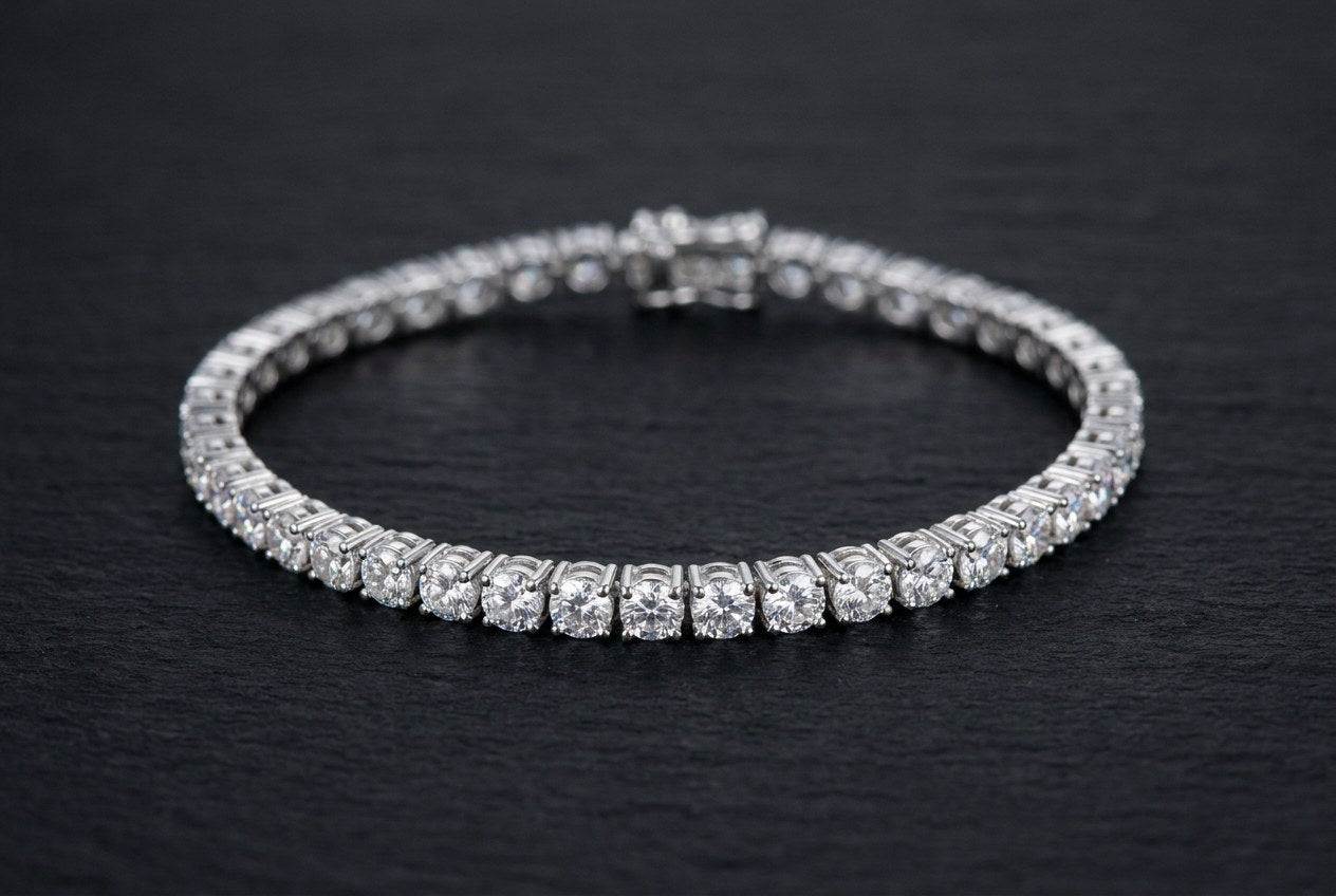 A 4mm round-cut moissanite tennis bracelet in polished .925 sterling silver curved on a dark stone surface