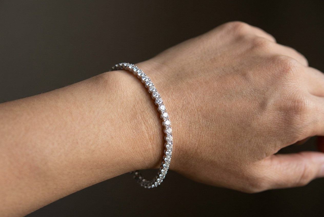 A moissanite tennis bracelet fastened on a wrist showing the correct relaxed fit and drape