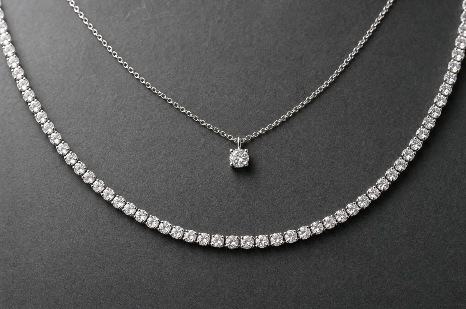 Pendant chain layered above a 4mm moissanite tennis chain with a visible gap between the two lengths