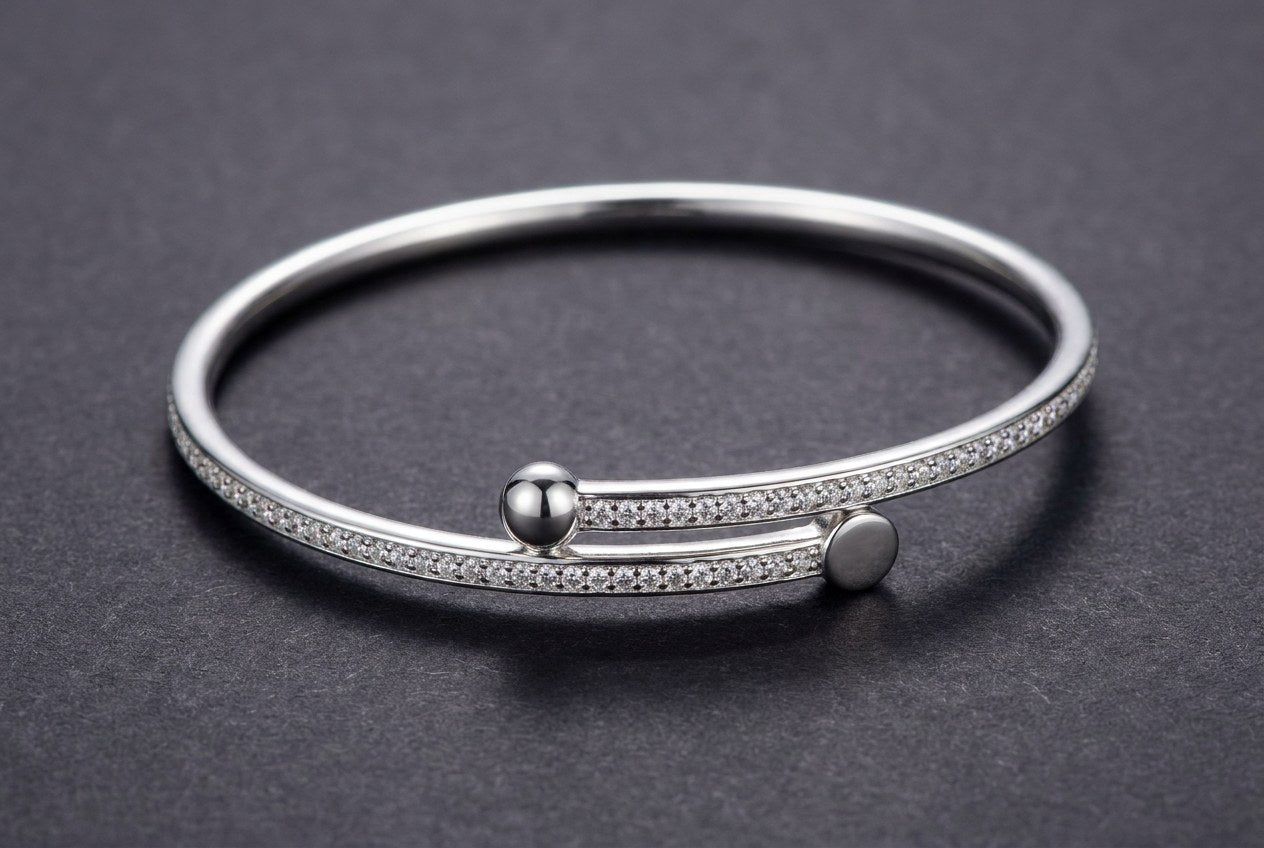 A rigid open sterling silver bangle whose two ends overlap without meeting in a clasp