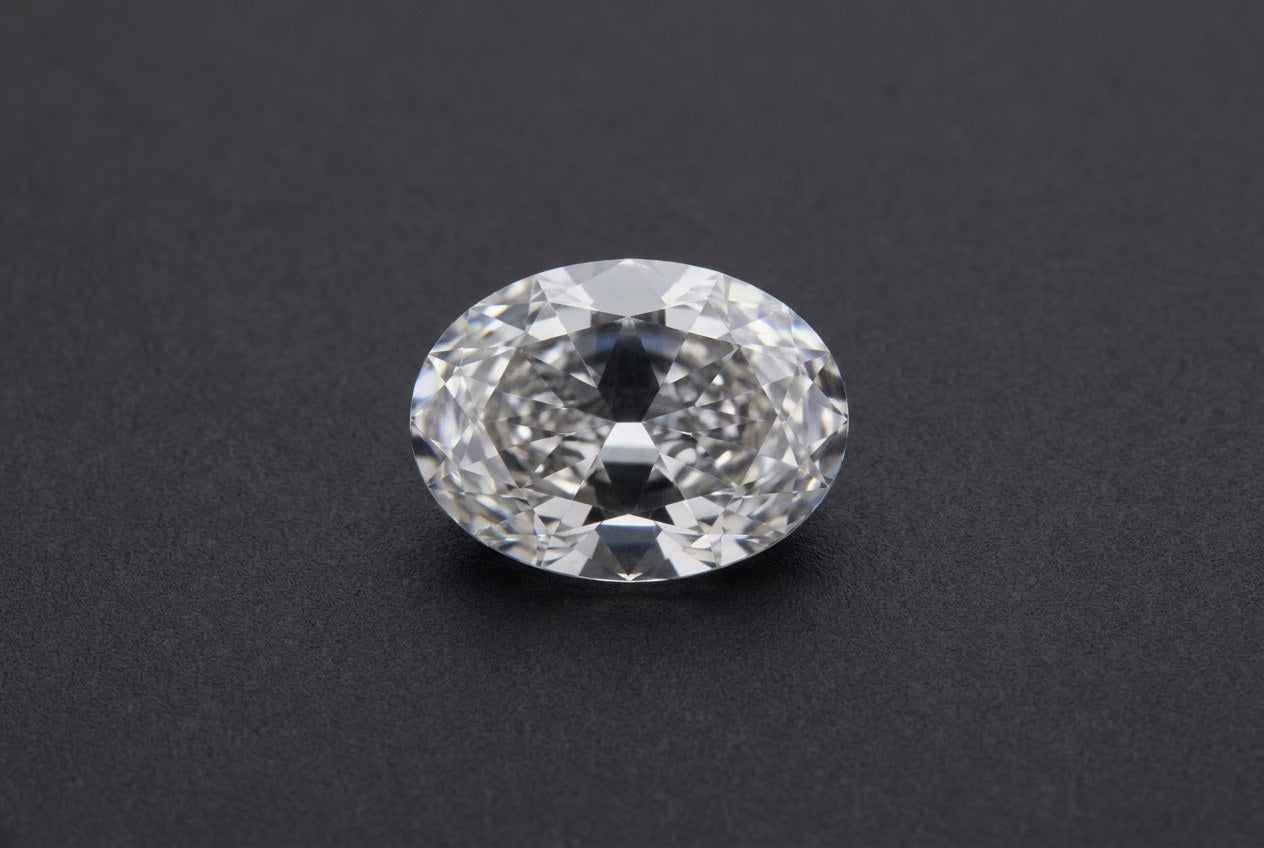 Oval moissanite viewed face up with a soft darker band across its narrow middle, the bow tie effect