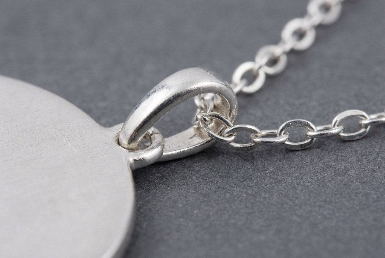 Close up of a pendant bail with a fine silver chain passing through the loop, showing the clearance between them