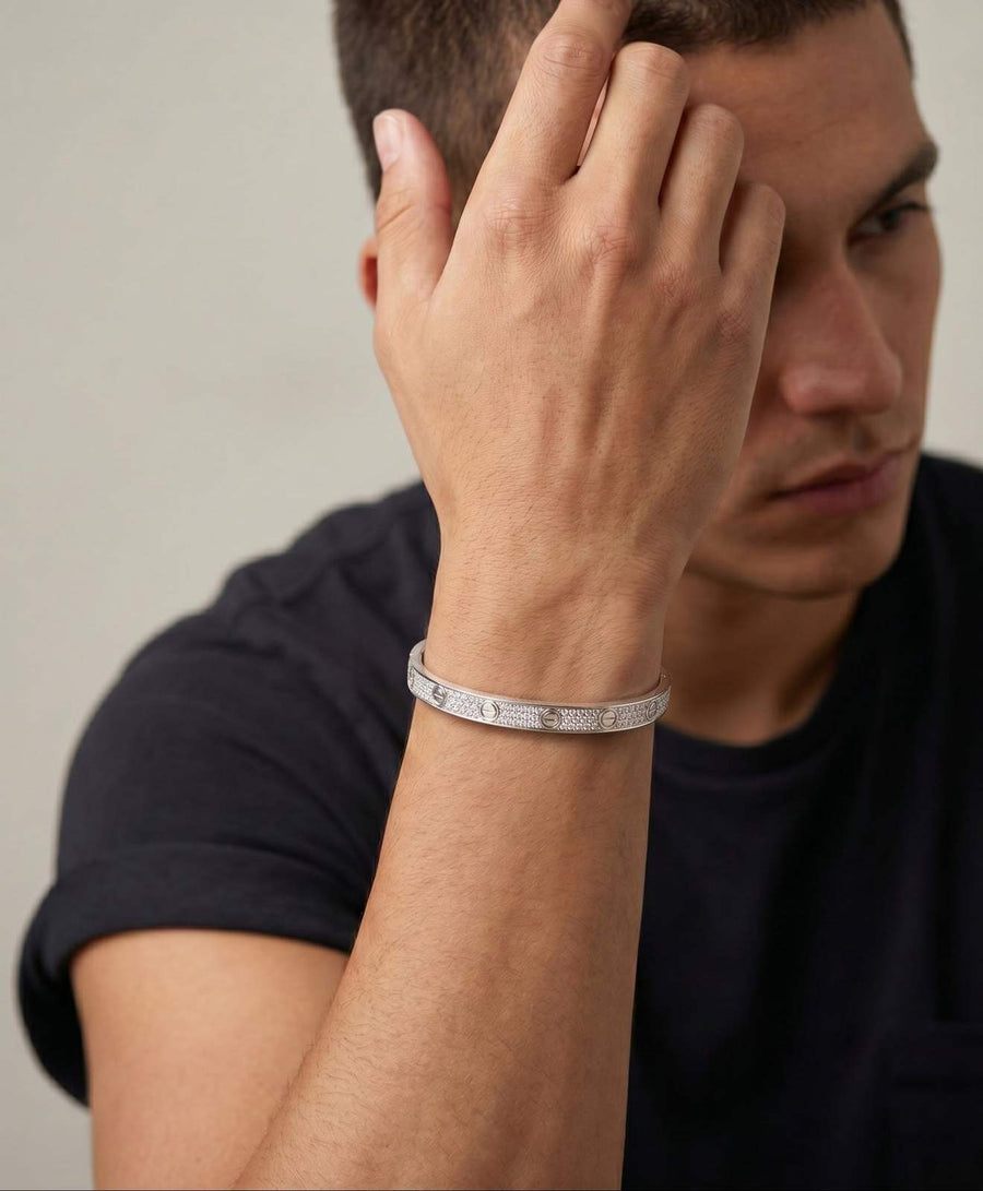 A person in a black t-shirt holds their hand near their face, showcasing the 'Forever Tied' Signature Love Band on their wrist against a plain background.