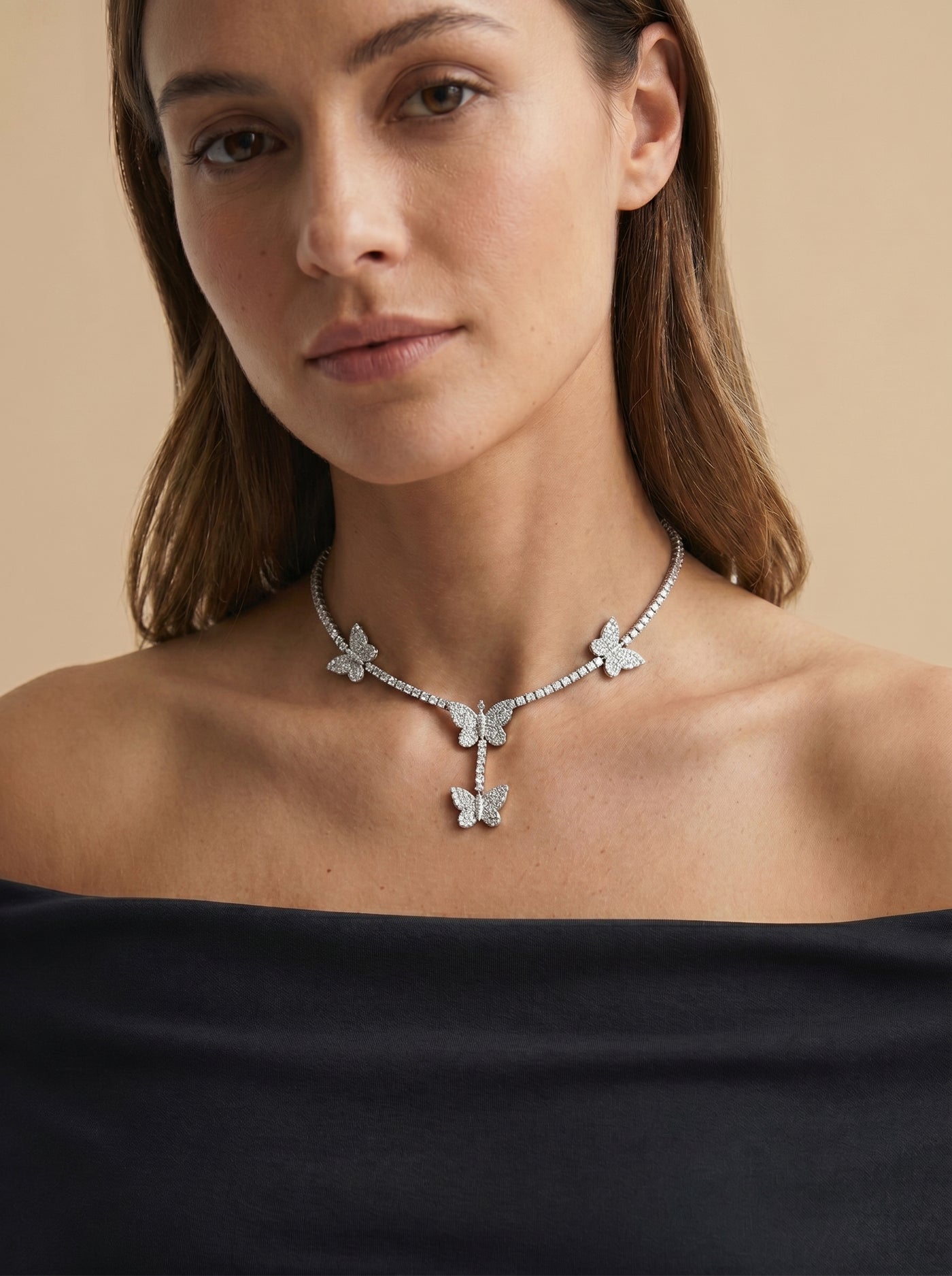 A woman wearing the Butterfly 'Dreamline' Tennis Chain featuring sparkling butterfly-shaped accents on a delicate silver tennis chain against a neutral background.