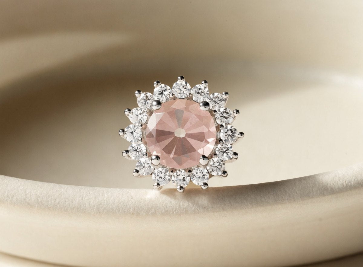 Close up of a halo stud earring with a pink center stone ringed by small clear stones