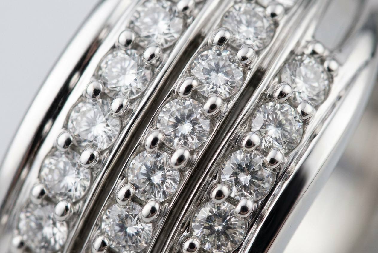 Macro close-up of prong-set clear round stones in polished sterling silver, showing the channels between settings