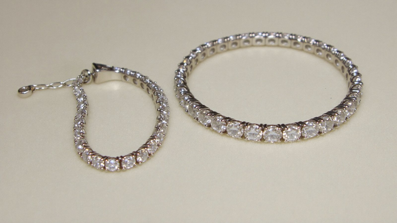 Two moissanite tennis bracelets in sterling silver side by side showing a slim and a wider stone width