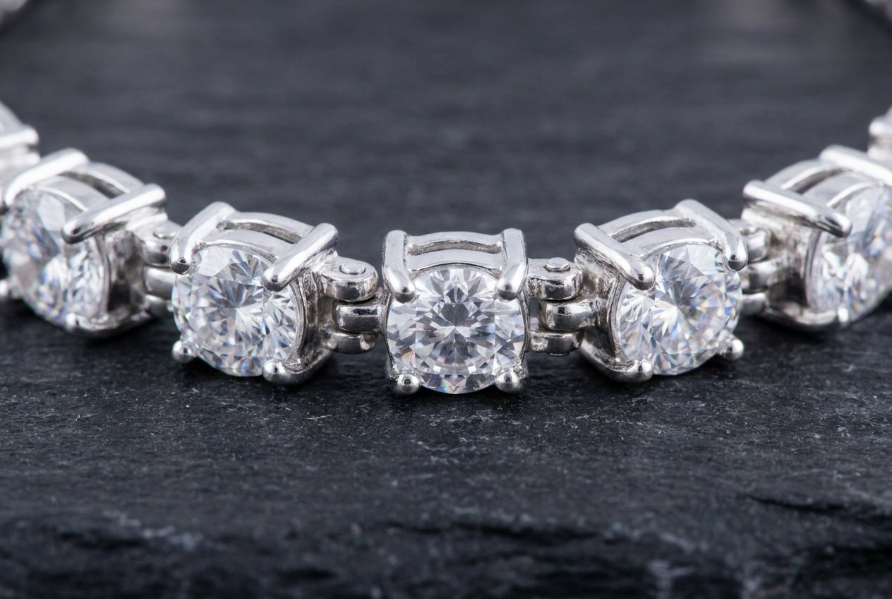 Close view of a sterling silver tennis bracelet showing four prongs curving over each round moissanite stone