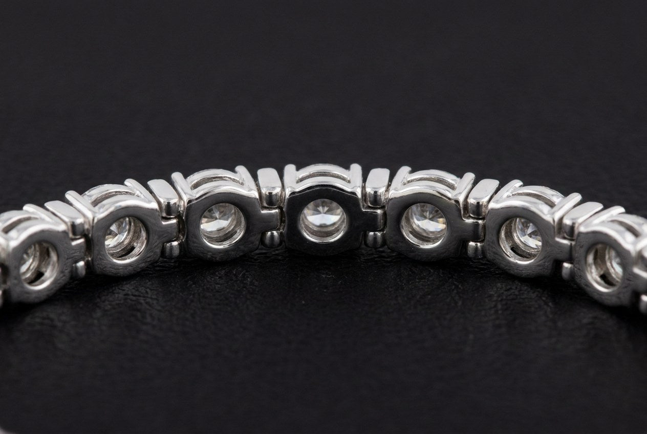 Underside of a silver tennis bracelet showing an open window in the metal behind each stone