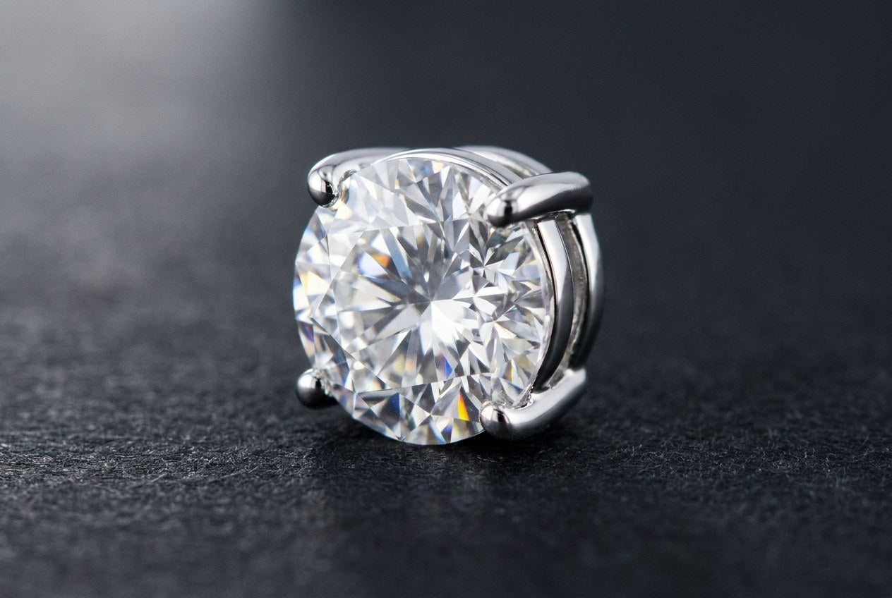 Macro view of a single round moissanite held by four prongs in a polished sterling silver setting