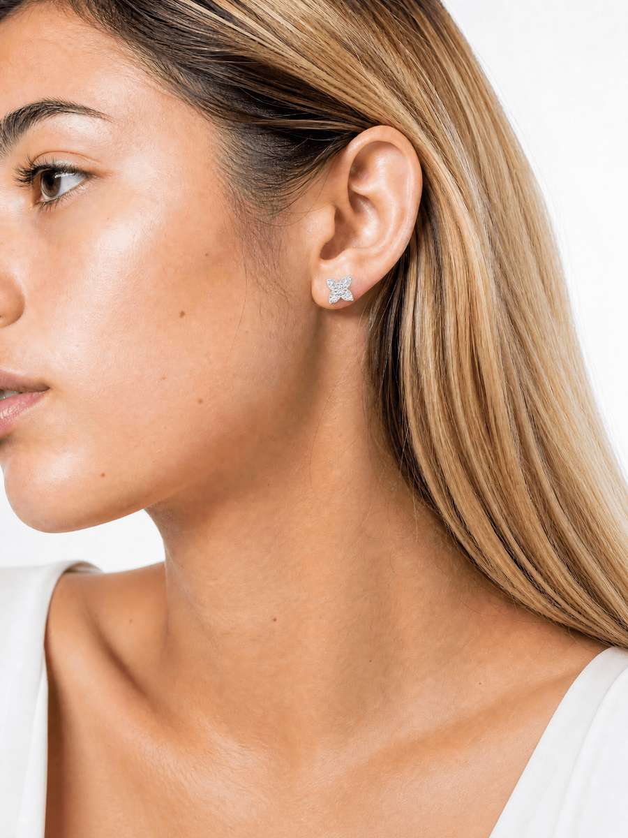 Close-up of a woman wearing Sophisticated Crossed Icon Earrings, showcasing delicate, sparkling jewelry that complements her natural skin tone and blonde hair.